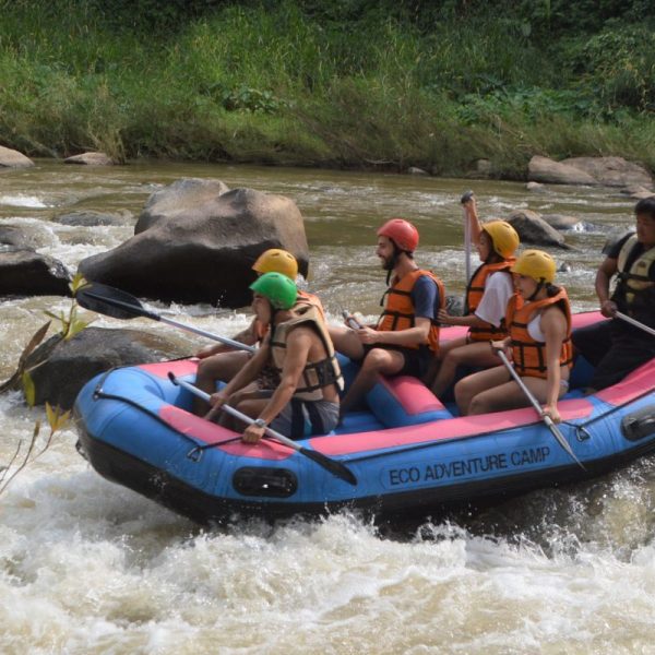 Group whitewater rafting in blue inflatable raft on a river.