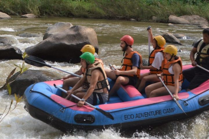 Group whitewater rafting in blue inflatable raft on a river.