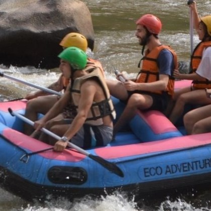 Group of people in helmets rafting on a river.