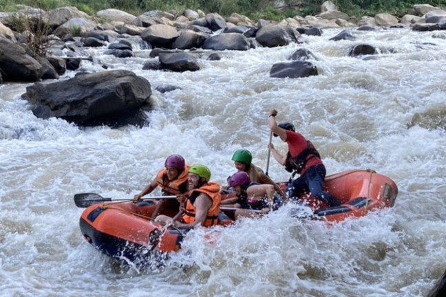 Group of people whitewater rafting on a rocky river.